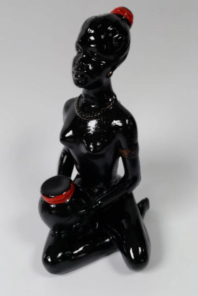 A chalkware piece depicting a young lady sitting with a vase